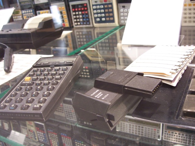 Al lado derecho hay un lector de tarjetas y unas tarjetas magneticas que la calculadora podia leer y escribir, usualmente contenian bibliotecas de programas. El lenguaje de programacion era poco mas que un assembler con un poquito de azucar sintactico para expresar condiciones pero casi nada mas.

On the right side there is a card reader and some magnetic cards that the calculator could read and write, usually they contained programming libraries. The programming language was little more than an assembler with a few syntactic sugar to express conditions but almost nothing else.