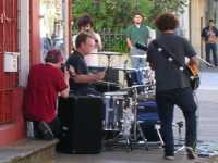
Un grupo tocando m�sica en la calle frente a una tienda de discos
A group playing music in the street in front of a record store
